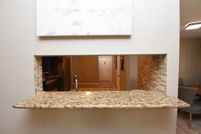 kitchen featuring sink, light hardwood / wood-style flooring, light stone countertops, fridge, and kitchen peninsula