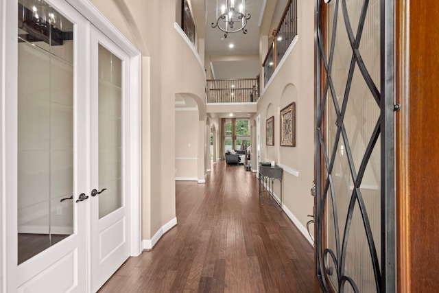 hallway with a chandelier, french doors, a high ceiling, and dark hardwood / wood-style floors