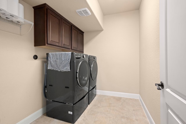 laundry room with washing machine and clothes dryer and cabinets