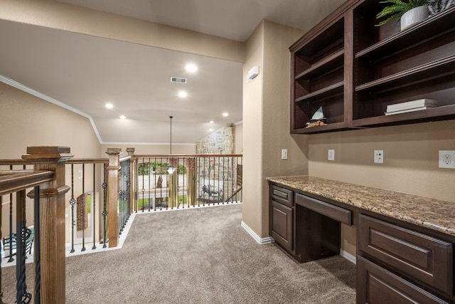 interior space with dark carpet, lofted ceiling, light stone countertops, built in desk, and dark brown cabinets