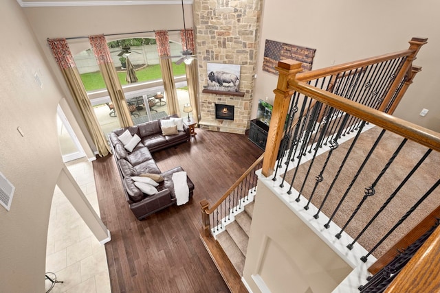 interior space featuring a fireplace, a towering ceiling, hardwood / wood-style flooring, and ceiling fan