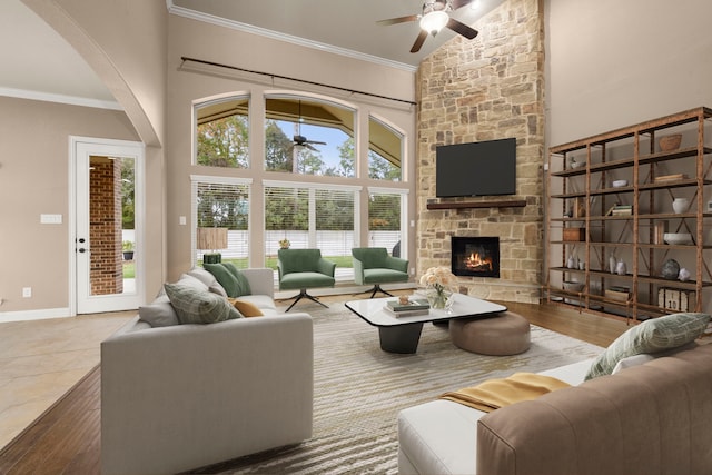 living room featuring wood-type flooring, a towering ceiling, a stone fireplace, and ornamental molding