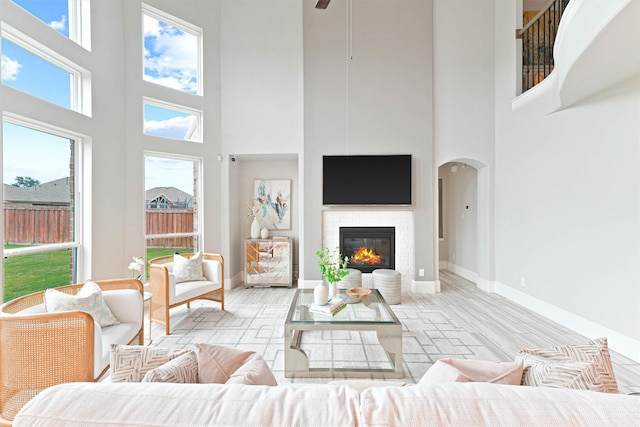 living room featuring a healthy amount of sunlight, light wood-type flooring, and a high ceiling