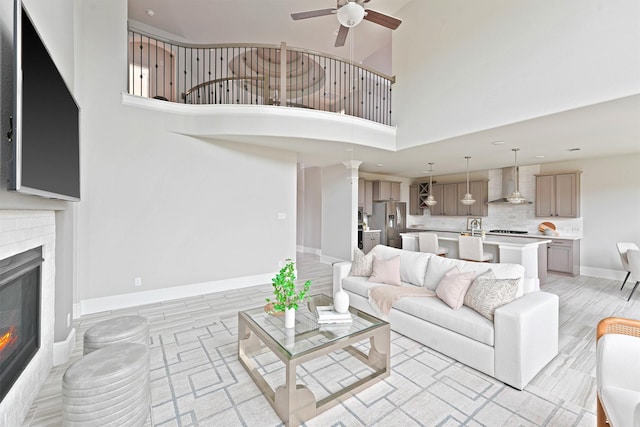 living room with ceiling fan, light wood-type flooring, and a high ceiling