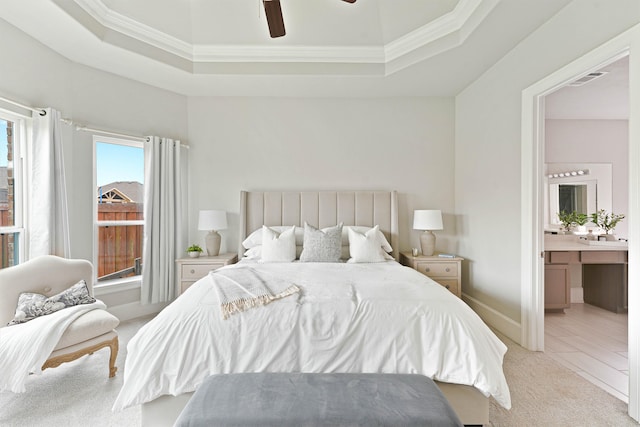 bedroom featuring connected bathroom, ceiling fan, crown molding, light colored carpet, and a tray ceiling