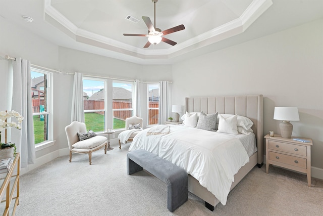 carpeted bedroom with a tray ceiling, ceiling fan, and crown molding