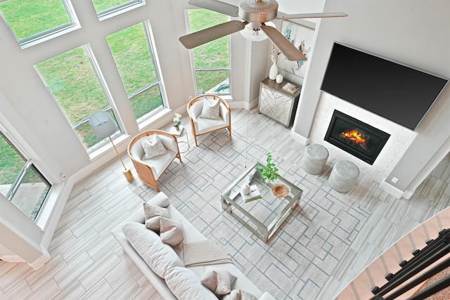 living room with ceiling fan, light wood-type flooring, and a high ceiling