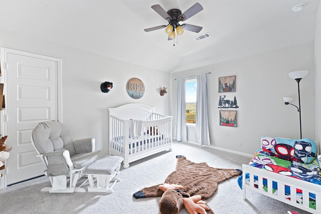 carpeted bedroom with a crib, ceiling fan, and lofted ceiling