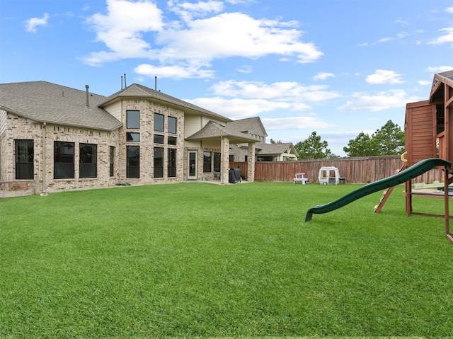 rear view of house with a playground and a lawn