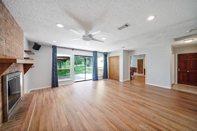 unfurnished living room with a brick fireplace, visible vents, light wood-style flooring, and baseboards