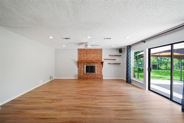 unfurnished living room featuring a brick fireplace, a textured ceiling, and light hardwood / wood-style flooring