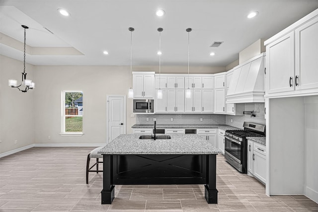 kitchen with light stone counters, stainless steel appliances, sink, white cabinets, and hanging light fixtures