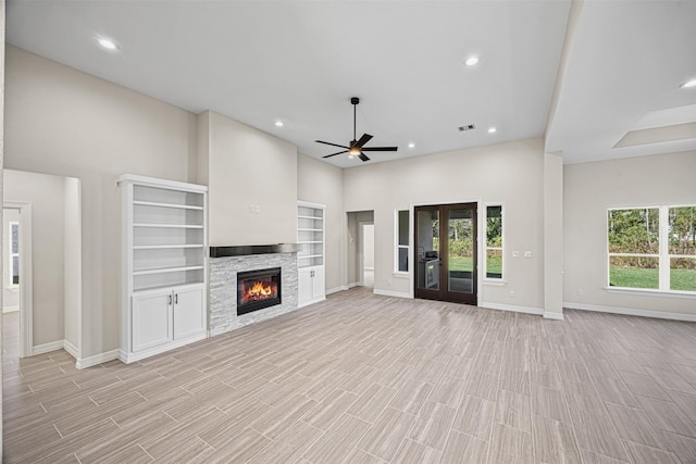 unfurnished living room with ceiling fan, a stone fireplace, and light hardwood / wood-style flooring