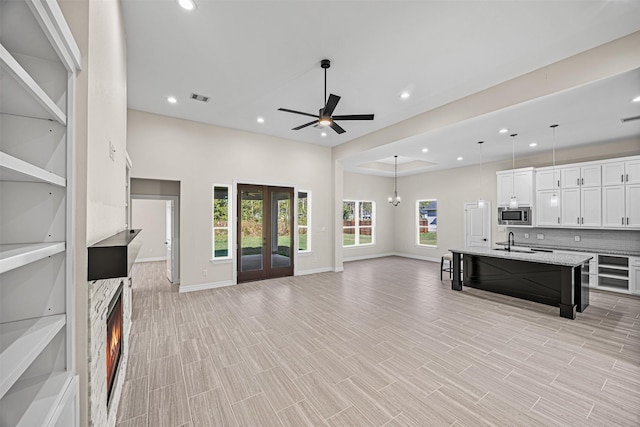 living room with french doors, light wood-type flooring, ceiling fan, and sink