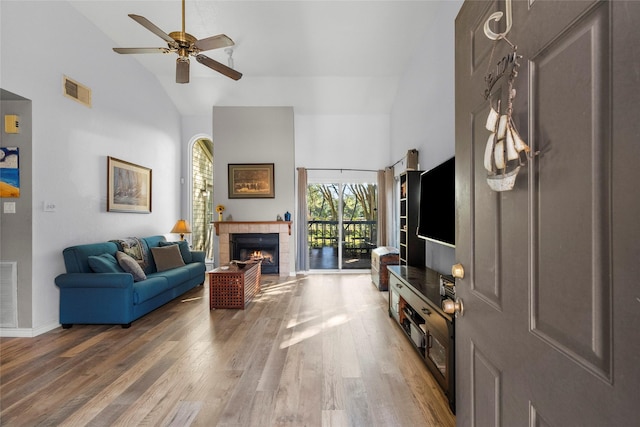 living room with ceiling fan, a fireplace, high vaulted ceiling, and hardwood / wood-style flooring