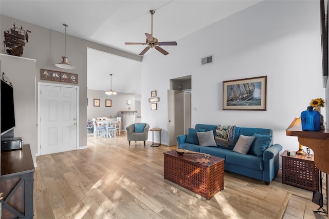 living room with ceiling fan, high vaulted ceiling, and light hardwood / wood-style flooring