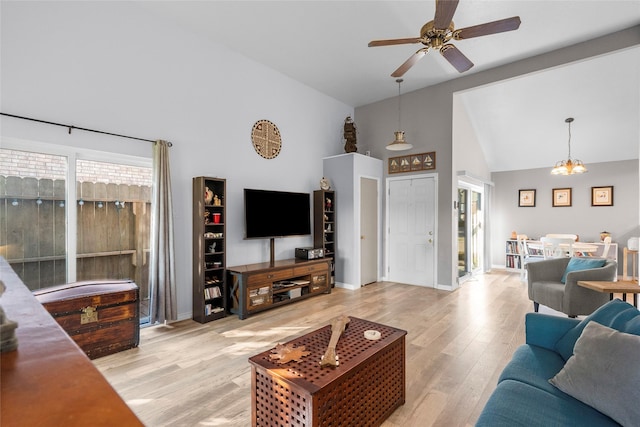 living room with light hardwood / wood-style flooring, high vaulted ceiling, and ceiling fan with notable chandelier