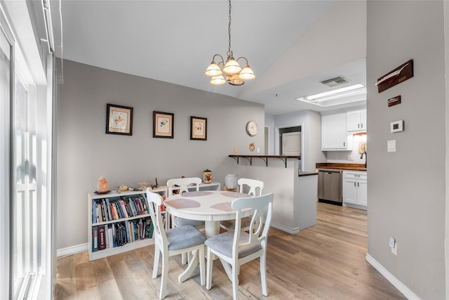 dining space with lofted ceiling, light hardwood / wood-style floors, and a notable chandelier