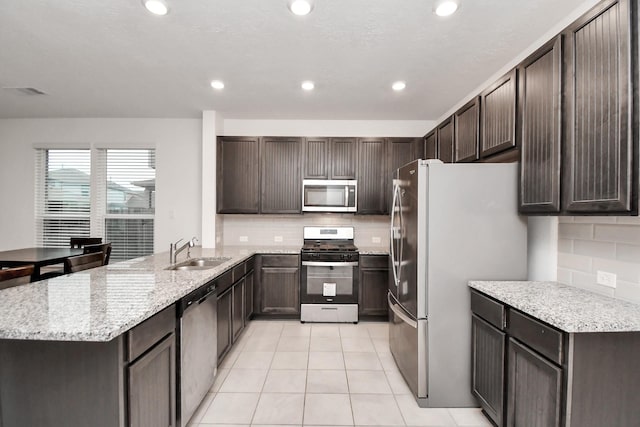 kitchen with sink, stainless steel appliances, kitchen peninsula, decorative backsplash, and light tile patterned flooring