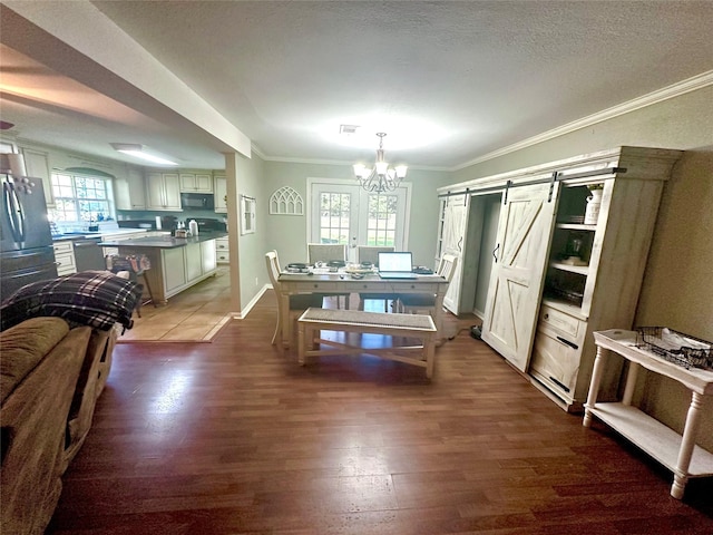 dining space featuring a barn door, ornamental molding, a healthy amount of sunlight, and hardwood / wood-style flooring