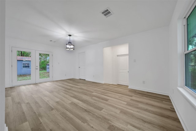 spare room featuring french doors, light hardwood / wood-style floors, and a notable chandelier