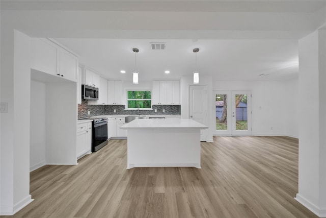 kitchen featuring a kitchen island, light hardwood / wood-style flooring, decorative light fixtures, white cabinets, and appliances with stainless steel finishes