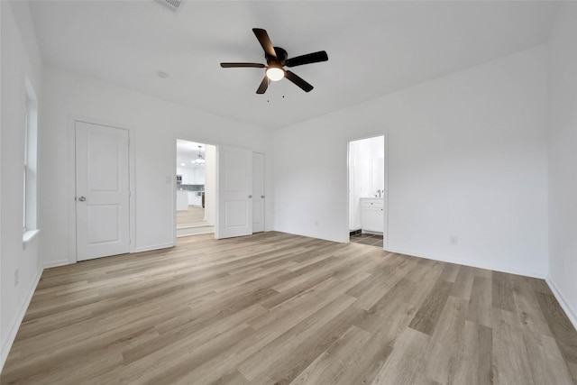 interior space featuring ceiling fan with notable chandelier, connected bathroom, and light hardwood / wood-style flooring