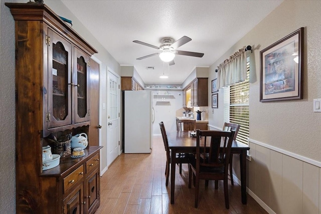 dining room with hardwood / wood-style floors, ceiling fan, and a textured ceiling