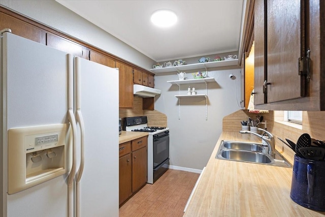 kitchen featuring light wood-type flooring, white appliances, backsplash, and sink