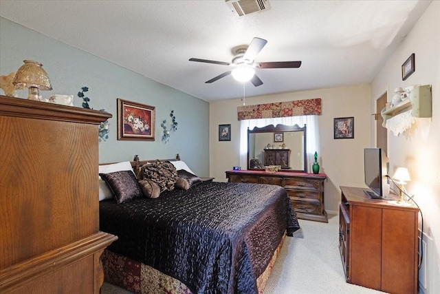 bedroom featuring ceiling fan, light colored carpet, and a textured ceiling