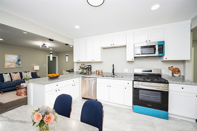 kitchen with sink, white cabinetry, decorative light fixtures, appliances with stainless steel finishes, and kitchen peninsula