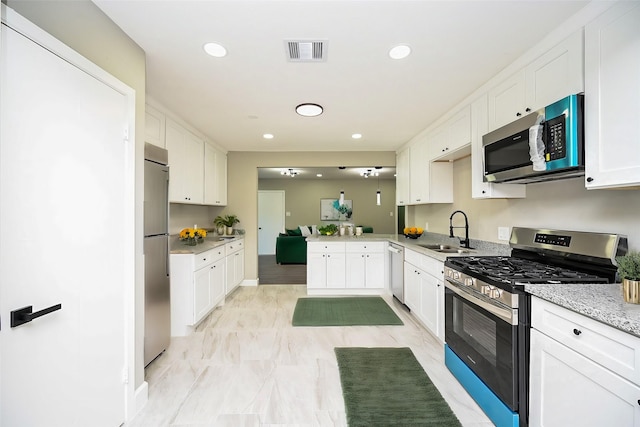 kitchen featuring sink, kitchen peninsula, white cabinets, and appliances with stainless steel finishes