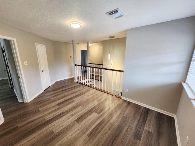 unfurnished room with a textured ceiling and dark hardwood / wood-style flooring