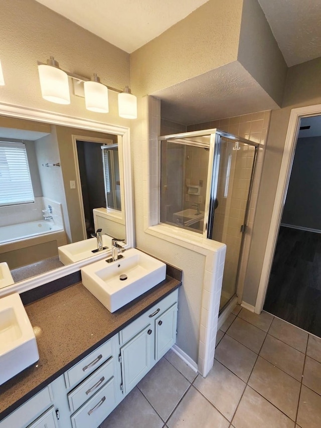 bathroom featuring tile patterned flooring, vanity, a textured ceiling, and plus walk in shower