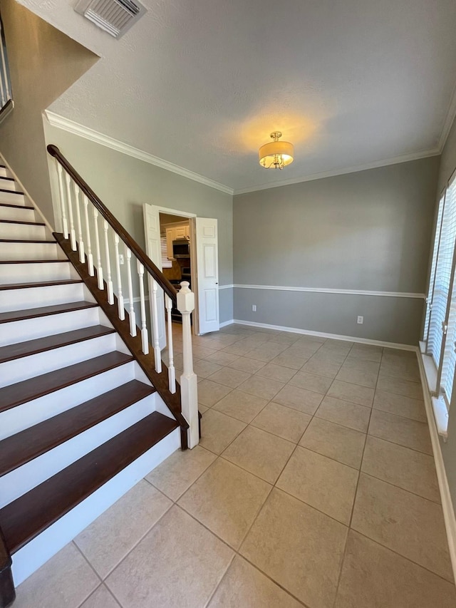 interior space featuring light tile patterned floors, a textured ceiling, and ornamental molding