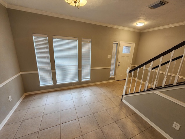 tiled foyer entrance with a textured ceiling and crown molding