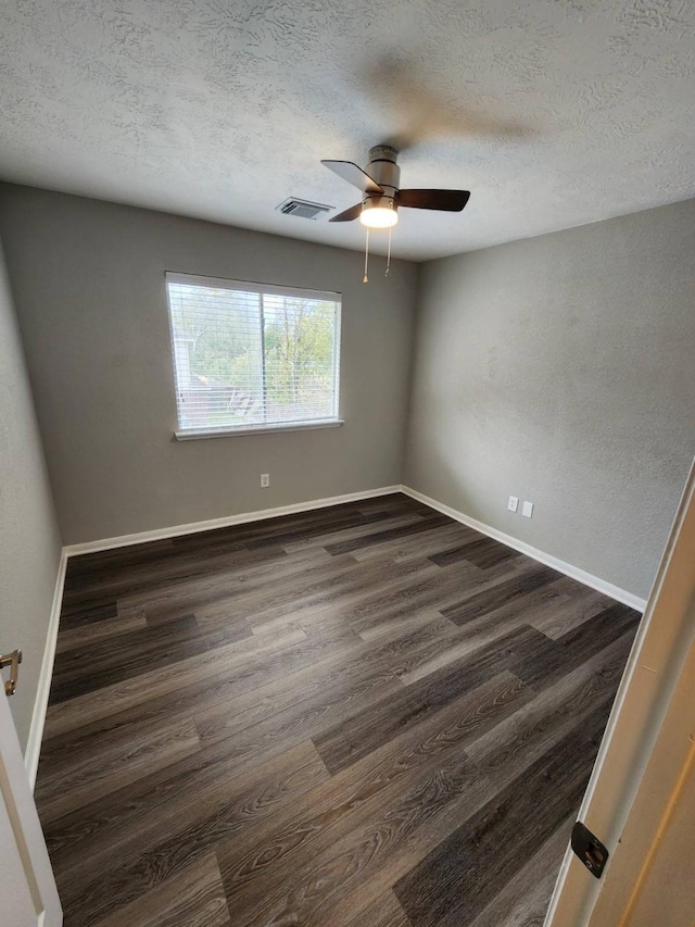 empty room featuring a textured ceiling, ceiling fan, and dark wood-type flooring