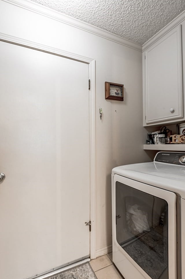 washroom with cabinets, light tile patterned floors, a textured ceiling, ornamental molding, and washer / clothes dryer