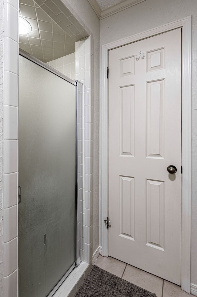 bathroom with crown molding, tile patterned flooring, and an enclosed shower