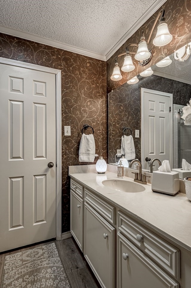 bathroom featuring vanity, wood-type flooring, a textured ceiling, and ornamental molding