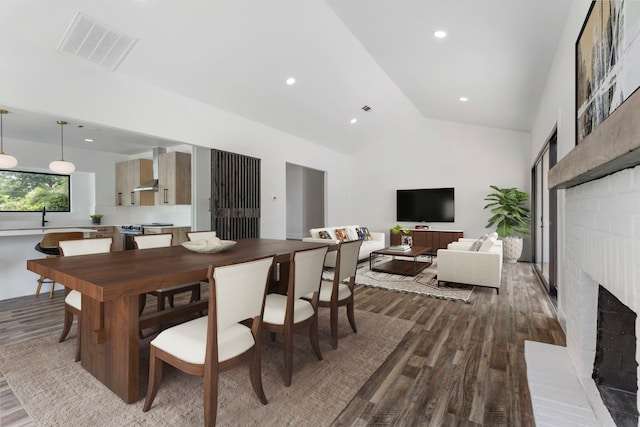 dining area with hardwood / wood-style flooring, vaulted ceiling, and a brick fireplace