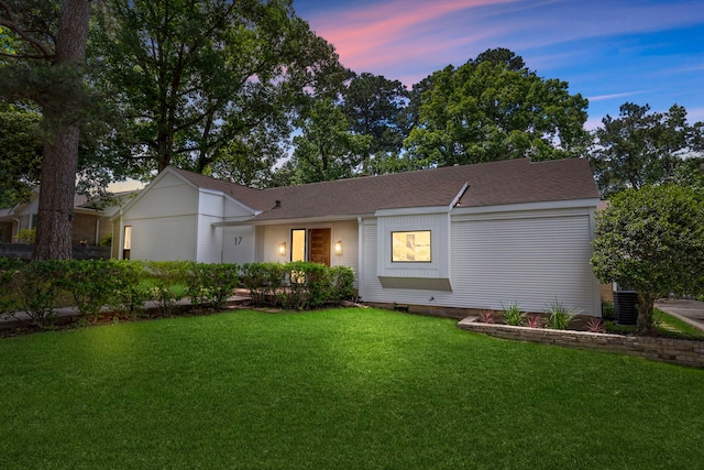 ranch-style house with central air condition unit and a lawn