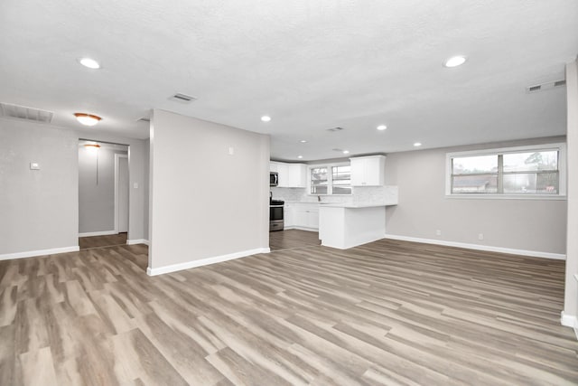 unfurnished living room featuring a textured ceiling and light hardwood / wood-style floors