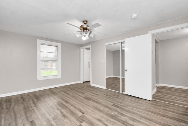 unfurnished bedroom with hardwood / wood-style flooring, ceiling fan, and a closet