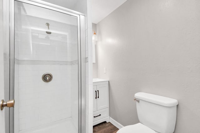 bathroom with a shower with door, vanity, wood-type flooring, and toilet