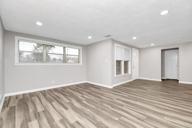 basement with a textured ceiling and light hardwood / wood-style flooring