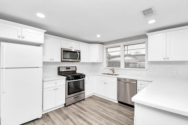 kitchen featuring white cabinets, sink, stainless steel appliances, and light hardwood / wood-style flooring