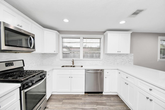 kitchen featuring light wood-type flooring, stainless steel appliances, white cabinetry, and sink