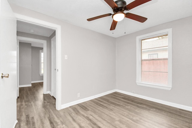 empty room with wood-type flooring, a wealth of natural light, and ceiling fan