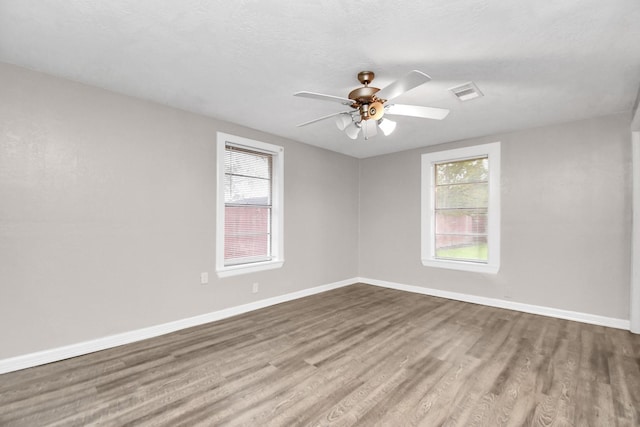 empty room featuring hardwood / wood-style floors, a textured ceiling, ceiling fan, and a healthy amount of sunlight